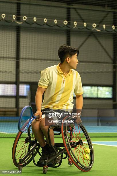 a handsome asian young teenage wheelchair tennis male player during an indoor session - wheelchair tennis stock pictures, royalty-free photos & images