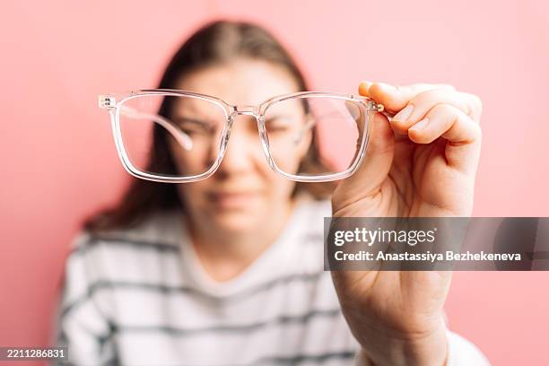 lady has poor vision and tries to look through glasses to improve vision, myopia - miopia foto e immagini stock