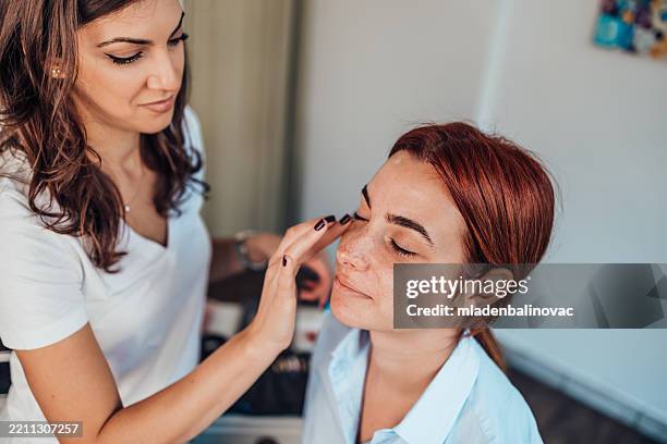 maquilleuse maquillant le visage d’une cliente dans un salon de beauté - maquillage professionnel photos et images de collection