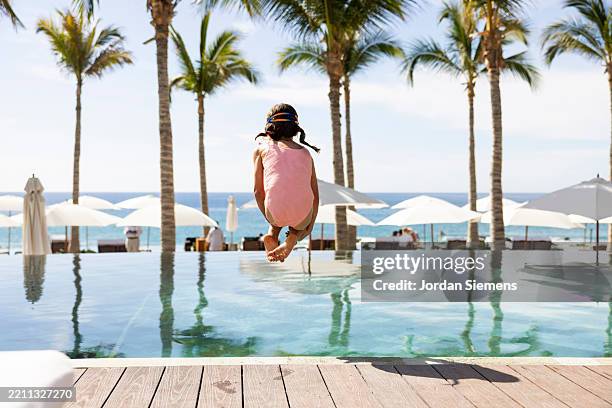 a young doing a cannonball into the pool. - young girl jumping into swimming pool stock pictures, royalty-free photos & images