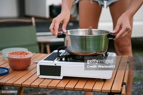 woman keeping pan on stove and cooking food during camping - camping stove stock pictures, royalty-free photos & images