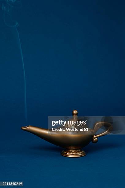 magic lamp with smoke on a blue background in a studio setting - magic lamp stock pictures, royalty-free photos & images