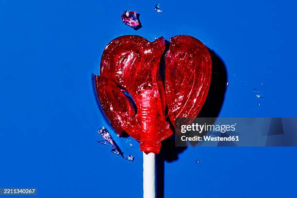 broken heart-shaped lollipop on a blue background symbolizing heartbreak - broken heart stock pictures, royalty-free photos & images