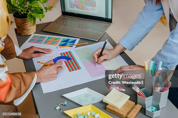 designers collaborating on a graphic design project at a modern desk - designers collaborating stock illustrations