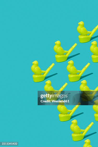 yellow plastic bird-shaped whistles arranged in a triangular formation on a blue background - bird swarm stock illustrations