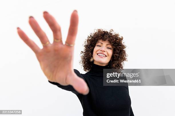 fashionable woman reaching out hand in black clothing against a white background - reaching stock pictures, royalty-free photos & images