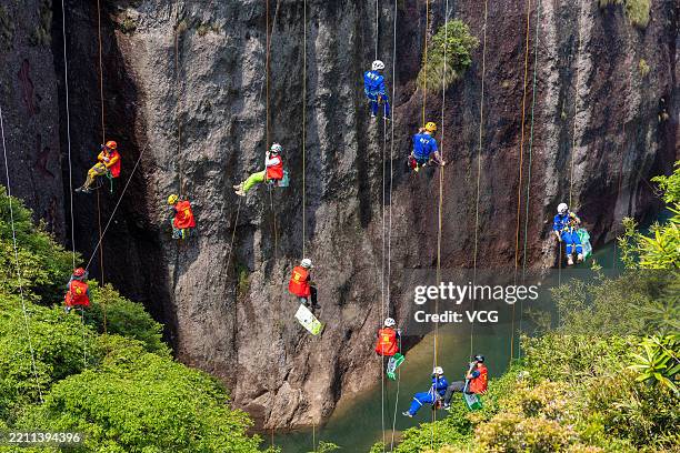 Volunteers descend the cliffs via safety ropes to clean garbage left by tourists on the cliffs on the Earth Day on April 22, 2025 in Taizhou,...