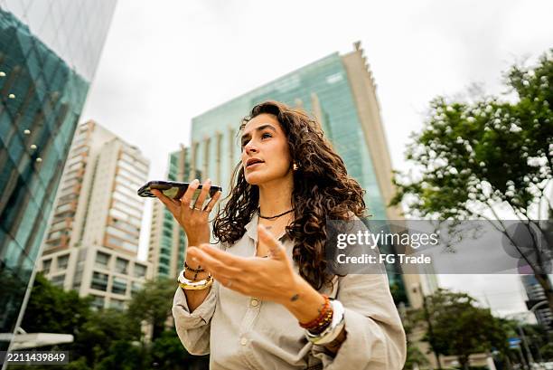 pansexual businesswoman talking on the mobile phone while walking in the street - conference phone stock pictures, royalty-free photos & images