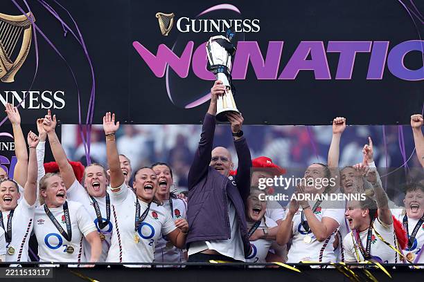 England's New Zealand head coach John Mitchell holds the six nations trophy as England players celebrate their win in the championship after the...