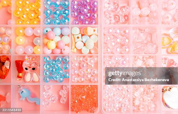a set of different beads for creating jewelry for diy in a plastic container on pink background - kawaii stock pictures, royalty-free photos & images