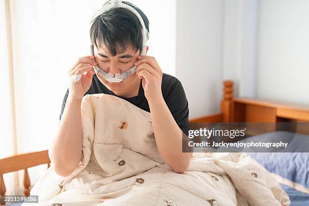 a man suffering from obstructive sleep apnea (osa) with tubes wrapped around him and use a cpap machine - nose tube stock pictures, royalty-free photos & images