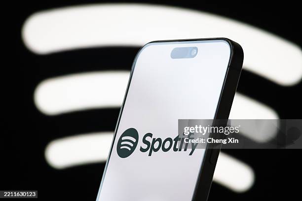 In this photo illustration, the logo of Spotify Technology S.A. Is displayed on a smartphone screen, with the company's iconic sound wave branding...