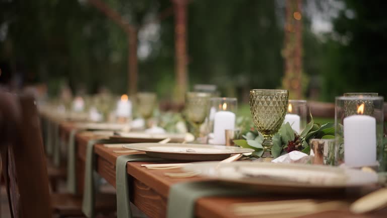 https://media.gettyimages.com/id/2211645857/video/elegant-outdoor-dining-setup-featuring-rustic-wooden-tables-and-decorative-greenery-in-a.jpg?b=1&s=640x640&k=20&c=tN5h7eCF-ROQgfQg-EF2cvbaIVXg_Ful_FXhqQVlY-0=