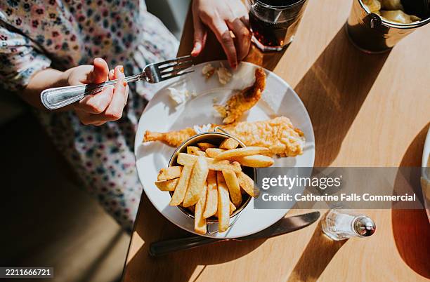top down image of a child eating two battered fish fillets and chips on a white plate - salt water fish stock pictures, royalty-free photos & images