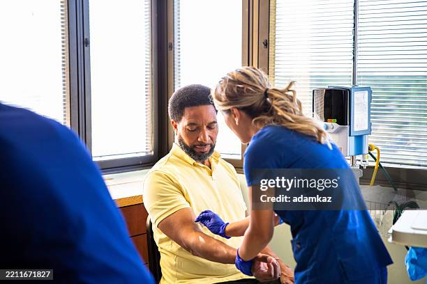 black man having blood drawn phlebotomy in hospital - doação de sangue imagens e fotografias de stock
