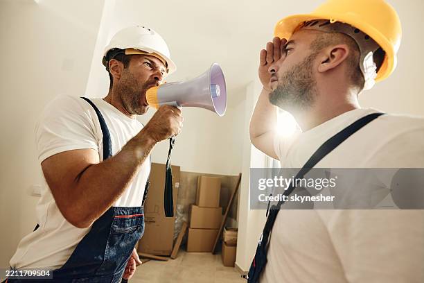 angry worker yelling through megaphone at his colleague. - work mistake stock pictures, royalty-free photos & images