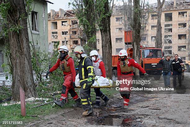 Rescue workers carry the body of a killed resident of an apartment building hit by a Russian missile on April 24, 2025 in Kyiv, Ukraine. In the early...