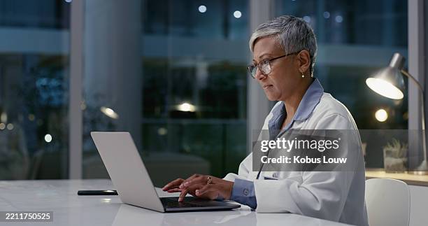 healthcare, woman and doctor with laptop for research, diagnosis information and reading at night. late, mature person and medical worker with digital for typing report, review treatment and hospital - health technology stock pictures, royalty-free photos & images