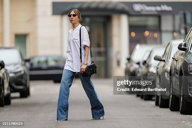 Emy Venturini wears a white oversized T-shirt from Balenciaga with a small logo on the chest. Hair is styled in a medium-length, light brown color...