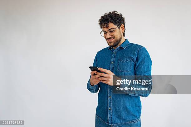 bel homme souriant utilisant un téléphone portable pour communiquer avec ses amis et sa famille - homme fond blanc photos et images de collection