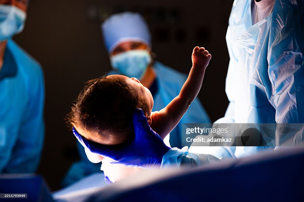 Bebé nacido y levantando el brazo y el puño durante el procedimiento de cesárea en el quirófano del hospital