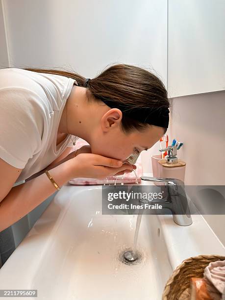 a young teenage girl washing face after applying skincare product - teen face mask stock pictures, royalty-free photos & images