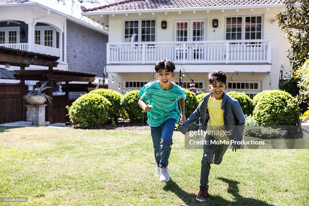 Young boys running in backyard of suburban home