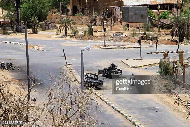 Sudanese men ride on a motorcycle past destroyed military vehicles in front of a hospital in Khartoum on April 28, 2025. The war in Sudan erupted on...