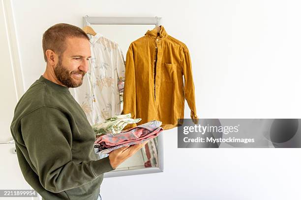 man evaluating his shirts for second hand sale - folded clean clothes stock pictures, royalty-free photos & images
