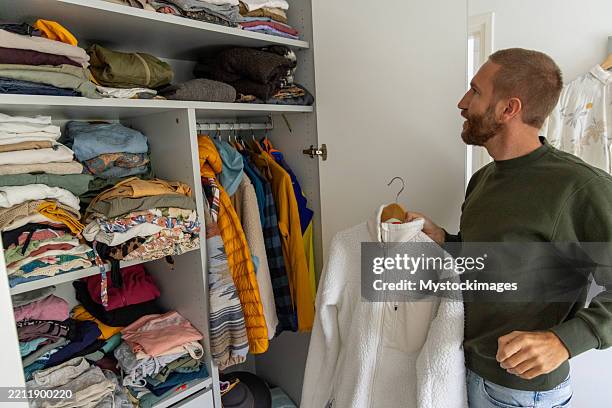 man selecting jacket from wardrobe - wardrobe stock pictures, royalty-free photos & images