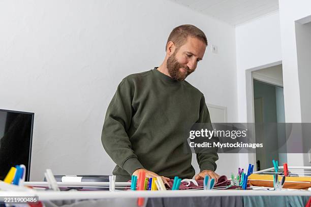 mann hängt wäsche drinnen auf wäscheständer - wäscheständer stock-fotos und bilder