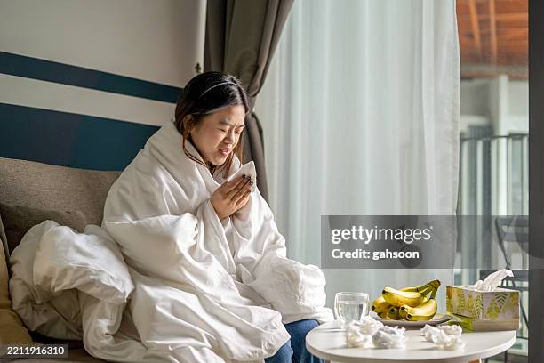 woman shiver at freezing apartment in warm blanket - immune system stock pictures, royalty-free photos & images