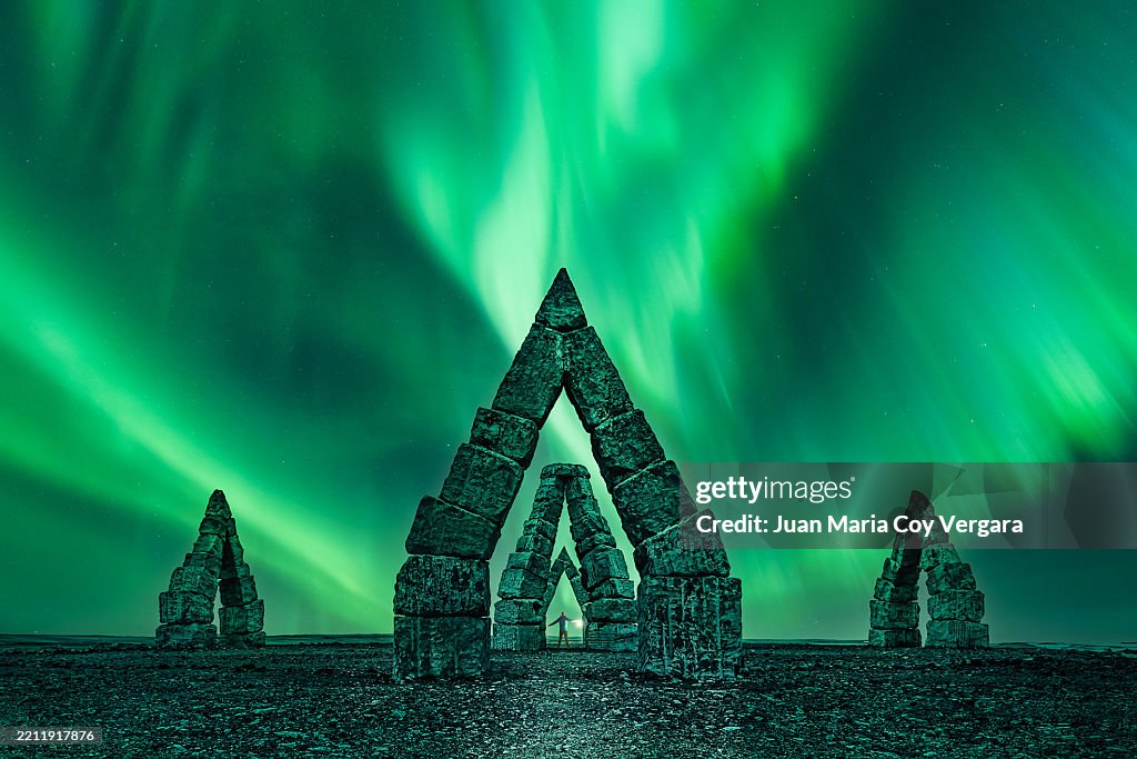 Tourist explorer stands under the arches enjoying at the breathtaking spectacle of the Northern Lights over the Arctic Henge in ¸é²¹³Ü´Ú²¹°ù³óö´Ú²Ô, ²Ñ±ð±ô°ù²¹°ì°ì²¹²õ±ôé³Ù³Ù²¹, Iceland