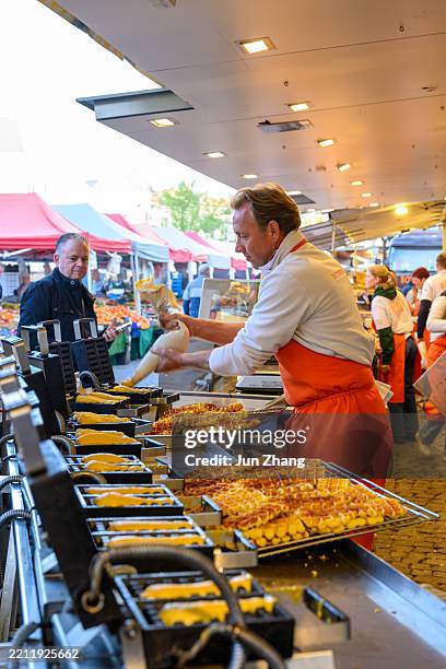 mechelen, belgium - vendor makes waffle at the saturday market on the grote markt square - market stall stock pictures, royalty-free photos & images