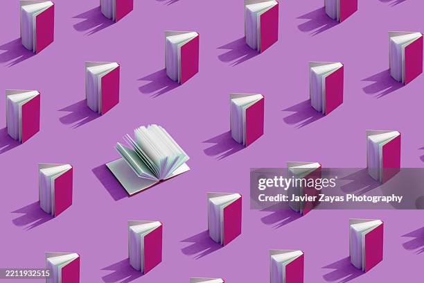 open book surrounded by closed books with purple covers on a purple background - publikation stock-fotos und bilder
