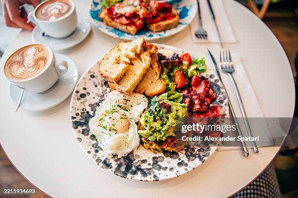 healthy breakfast with fried eggs, pancake, avocado and bacon served at a cafe - brunch imagens e fotografias de stock