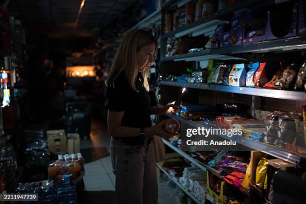 People shop for groceries using their phone as flashlight during a widespread power outage that struck Spain and Portugal around midday on Monday,...
