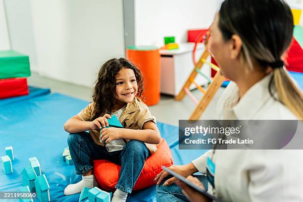 child boy playing with cubes and talking to therapist during therapy at clinic - alternatieve therapie stockfoto's en -beelden