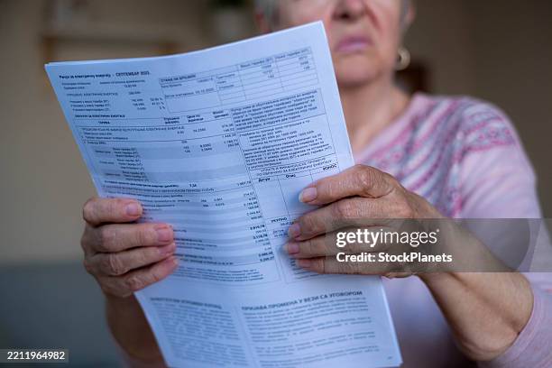grandma keeps household bills, looks at them, pays, sad - beak stock pictures, royalty-free photos & images