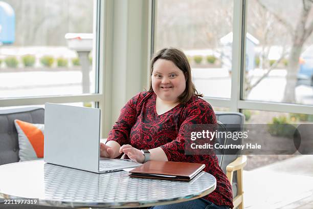 confident young woman with down syndrome working on laptop - disability computer stock pictures, royalty-free photos & images