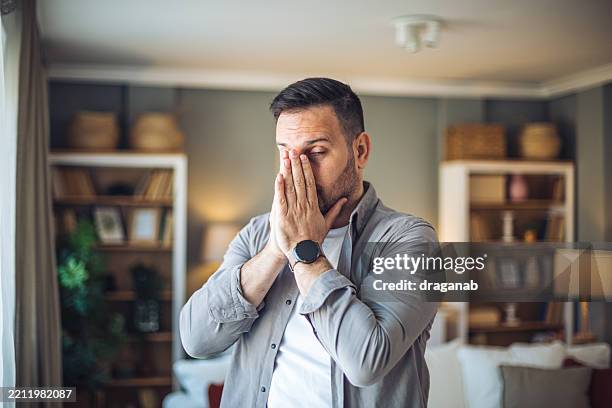 stressed man covering face with hands at home - verdict stock pictures, royalty-free photos & images