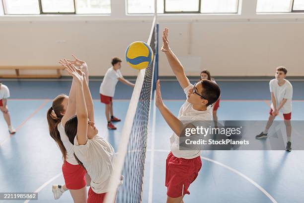 kinder trainieren volleyball in der halle - volleyballnetz stock-fotos und bilder