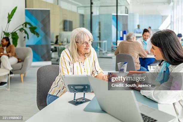 financial advisor discusses banking options with a senior client in a modern bank office setting - bankieren stockfoto's en -beelden