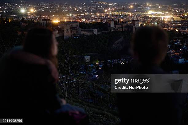 Two people look at a general view of Granada, with the Alhambra, plunged into darkness during the power outage that affects Spain nationwide in...
