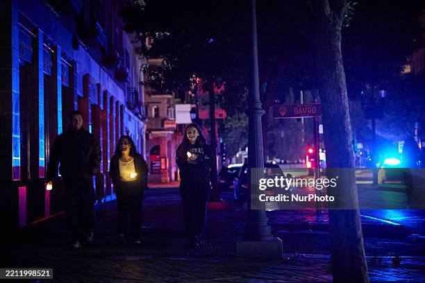 Three people walk down the street with candles during the power outage that affects Spain nationwide in Granada, Spain, on April 28, 2025. Power...