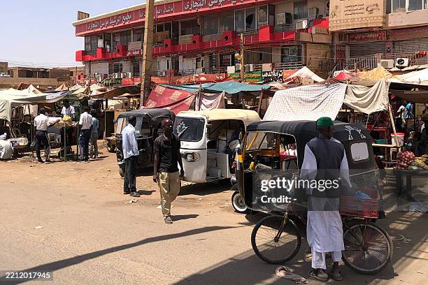 People walk past stalls in the capital Khartoum's southern neighbourhood of al-Kalakla on April 29, 2025. In the south of war-ravaged Khartoum,...