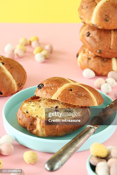 image of sliced toasted hot cross buns with easter eggs on sweet pastel pink and yellow background / festive baked treats - easter breakfast stock pictures, royalty-free photos & images
