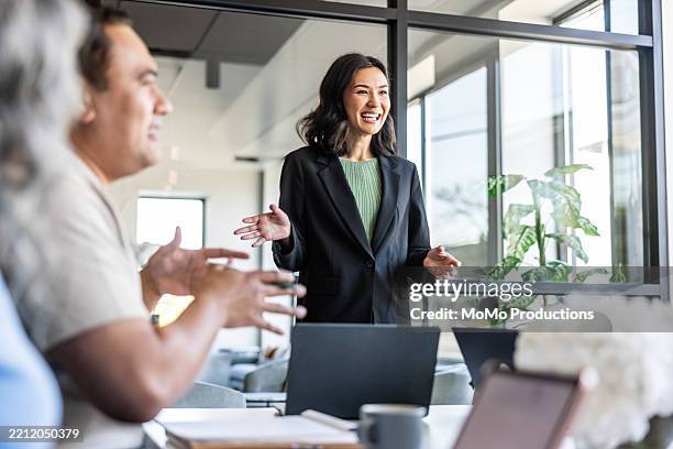 young businesswoman speaking to colleagues in modern conference room - líder fotografías e imágenes de stock