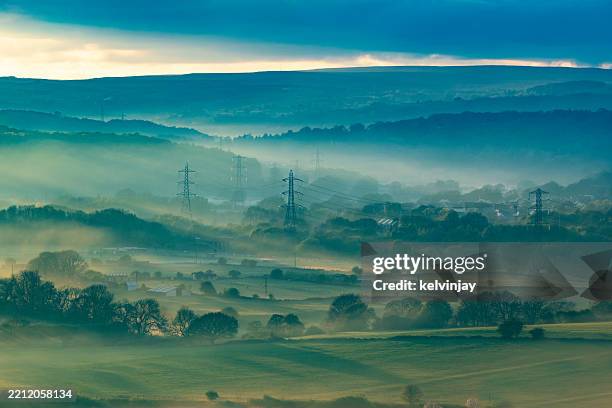 misty valley at sunset, showing electricity pylons - rede elétrica imagens e fotografias de stock