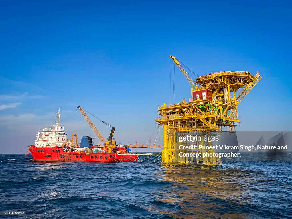 A Workboat / Accommodation and Work Vessel working at an offshore unmanned platform in the middle of the Arabian Sea, surrounded by deep blue waters and open ocean. .